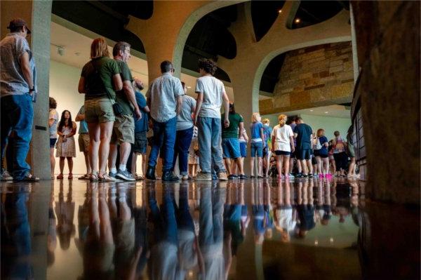  A long line of people are reflected into a shiny floor. 