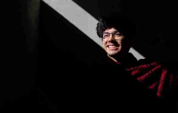  A portrait of a college student smiling while wearing a red poncho. 