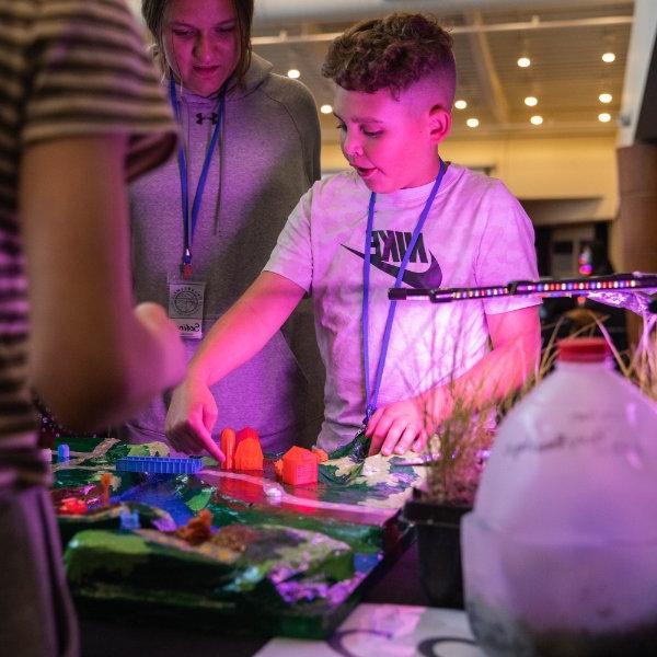 Student explains his research project to guests